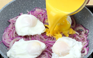 Выкладываем на сковороде слой лука, а потом жарим яичницу поверх него. Яйца становятся похожи на пирог